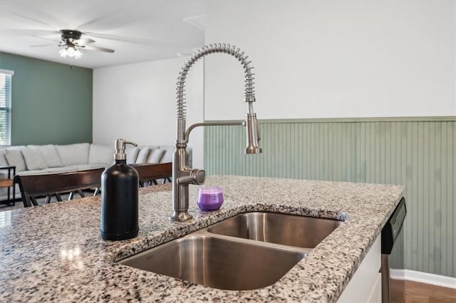 kitchen featuring dark wood-type flooring, sink, stainless steel dishwasher, ceiling fan, and light stone countertops