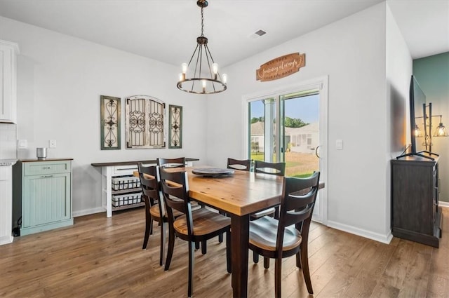 dining space with dark hardwood / wood-style floors and a notable chandelier