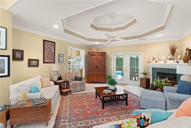 117 Serenoa Dr, Brunswick, GA 31523 - living room featuring light tile patterned floors, crown molding, a ceiling fan, a raised ceiling, and a warm lit fireplace