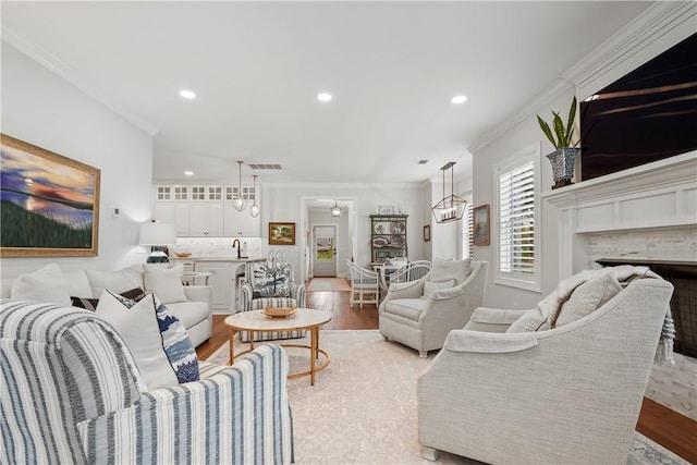 living room with visible vents, a chandelier, ornamental molding, recessed lighting, and light wood-style flooring