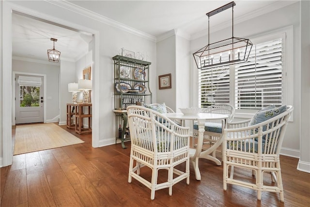 dining area featuring a chandelier, baseboards, wood finished floors, and ornamental molding