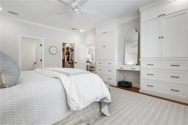 bedroom with visible vents, wood finished floors, ornamental molding, and a spacious closet