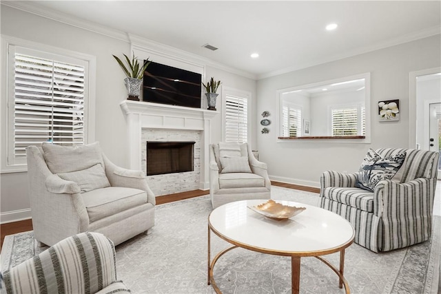 living room featuring baseboards, a fireplace, wood finished floors, and crown molding