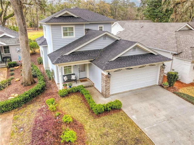 traditional-style home with brick siding, an attached garage, driveway, and roof with shingles