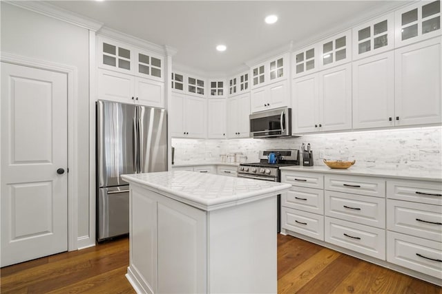 kitchen with dark wood-type flooring, backsplash, a kitchen island, appliances with stainless steel finishes, and light countertops