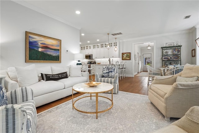 living area featuring light wood-type flooring, visible vents, recessed lighting, and crown molding