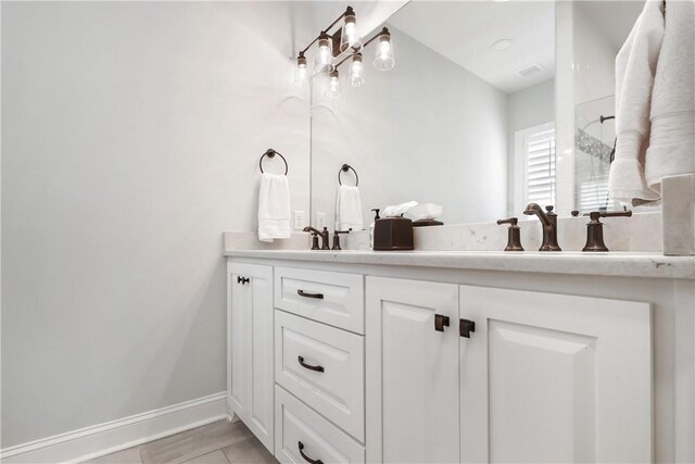 bathroom with a sink, an inviting chandelier, baseboards, and double vanity