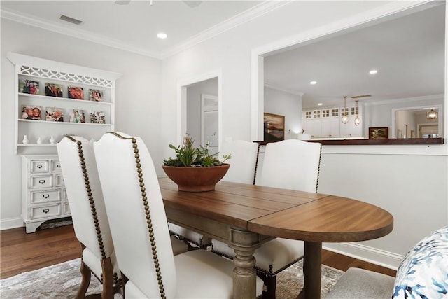 dining room with dark wood finished floors, visible vents, and ornamental molding