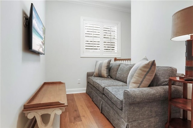 living area with baseboards, wood finished floors, and ornamental molding