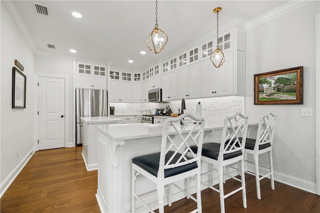 kitchen with a peninsula, stainless steel appliances, decorative backsplash, light countertops, and dark wood-type flooring