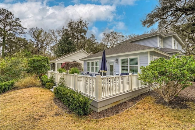 rear view of property featuring roof with shingles and a wooden deck