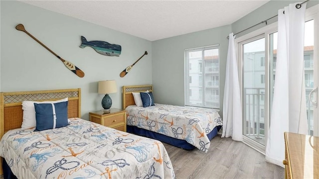 bedroom with light wood-type flooring, a textured ceiling, and access to outside