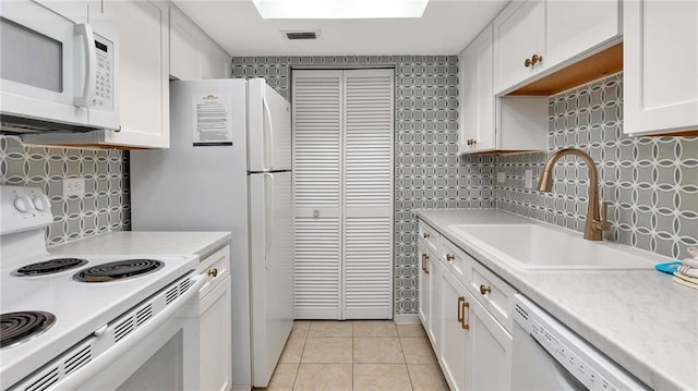 kitchen featuring white cabinetry, sink, tasteful backsplash, white appliances, and light tile patterned flooring