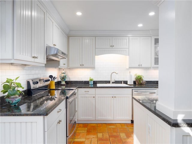 kitchen featuring electric stove, sink, white cabinetry, decorative backsplash, and dark stone counters