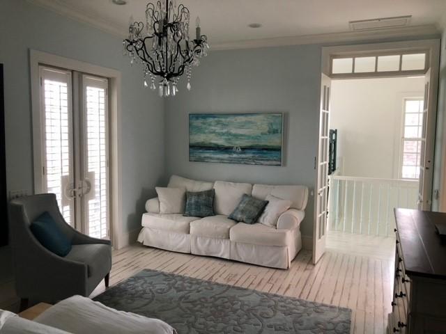 living area featuring a notable chandelier, french doors, wood finished floors, and ornamental molding