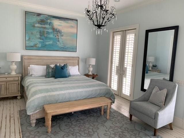 bedroom featuring ornamental molding, access to exterior, french doors, light wood-type flooring, and a chandelier