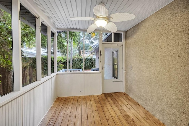 unfurnished sunroom featuring ceiling fan, a healthy amount of sunlight, and wooden ceiling