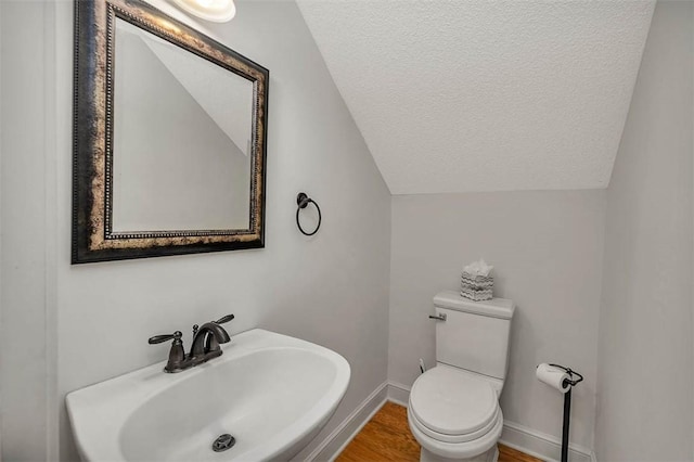 bathroom featuring a textured ceiling, hardwood / wood-style flooring, lofted ceiling, and sink