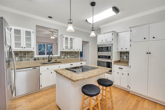 kitchen featuring sink, a kitchen island, decorative backsplash, white cabinets, and appliances with stainless steel finishes