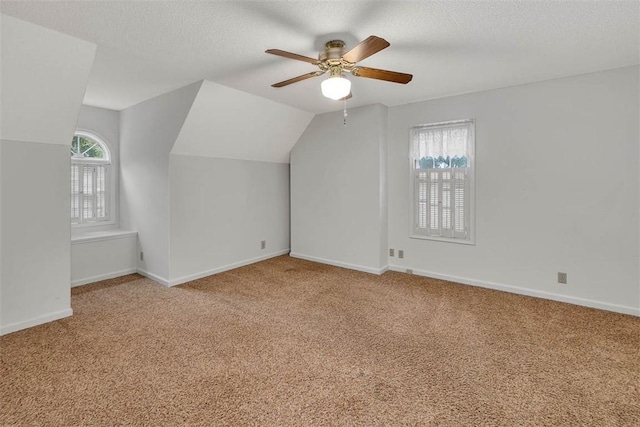 bonus room with ceiling fan, light colored carpet, a textured ceiling, and vaulted ceiling