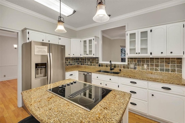 kitchen with light wood-type flooring, stainless steel appliances, sink, white cabinetry, and hanging light fixtures