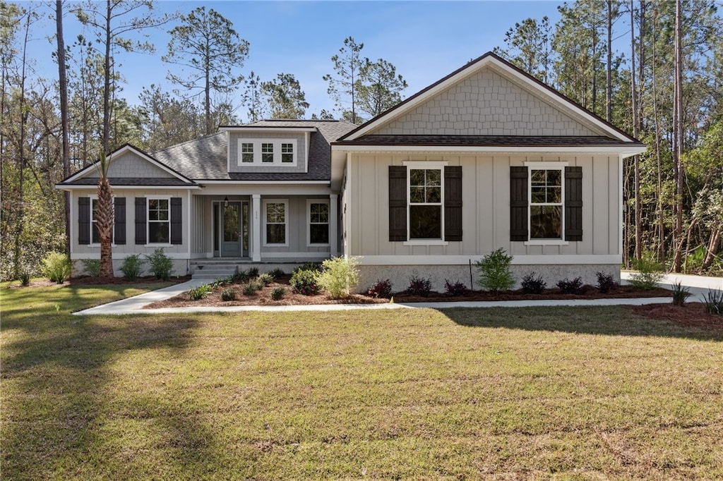 craftsman house featuring board and batten siding, a front yard, and roof with shingles