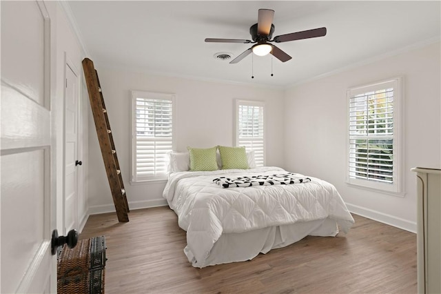 bedroom with crown molding, wood-type flooring, and ceiling fan