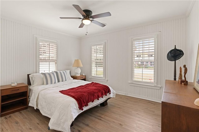 bedroom featuring hardwood / wood-style flooring, ornamental molding, and ceiling fan