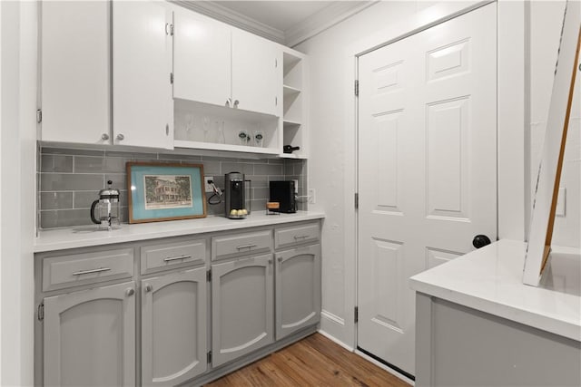 kitchen featuring tasteful backsplash, ornamental molding, gray cabinets, and light hardwood / wood-style floors