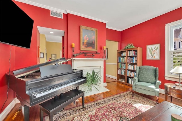 sitting room featuring visible vents, baseboards, wood finished floors, and crown molding