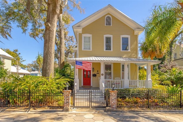 view of front of property featuring a gate, covered porch, a fenced front yard, and metal roof