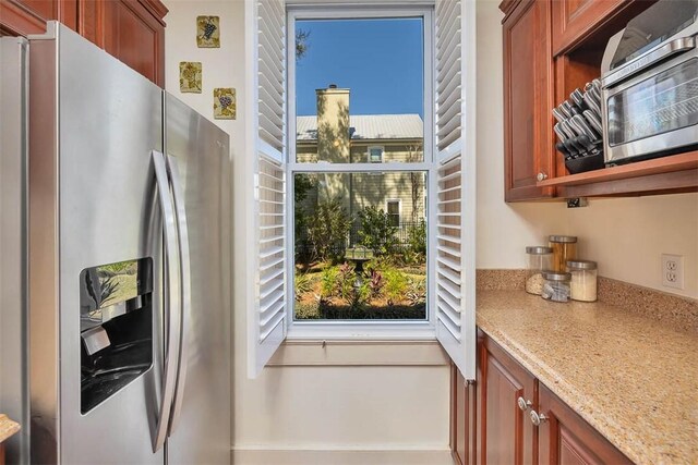 kitchen featuring light stone counters and stainless steel refrigerator with ice dispenser