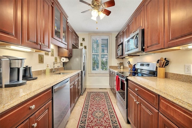 kitchen featuring light tile patterned flooring, appliances with stainless steel finishes, light stone countertops, and a sink