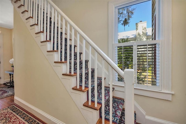 stairs with a wealth of natural light, baseboards, and wood finished floors