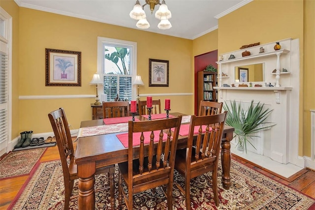 dining area featuring baseboards, crown molding, an inviting chandelier, and wood finished floors