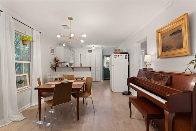 dining area with ornamental molding, light hardwood / wood-style flooring, and a notable chandelier