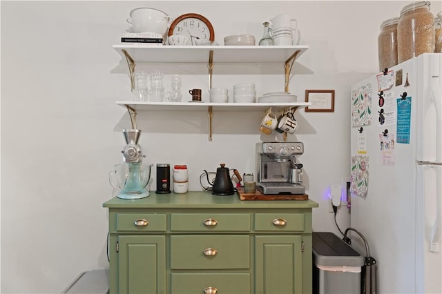 bar with white refrigerator and green cabinets