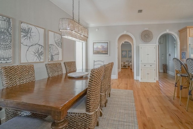 dining room with light hardwood / wood-style flooring, an inviting chandelier, vaulted ceiling, and ornamental molding