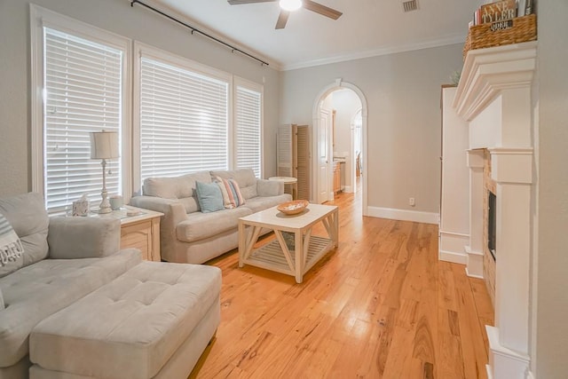 living room featuring ceiling fan, ornamental molding, and light wood-type flooring