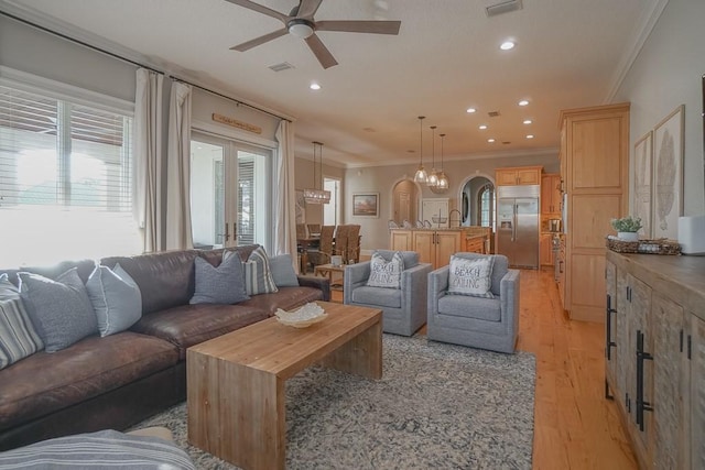 living room with light wood-type flooring, ceiling fan, and ornamental molding