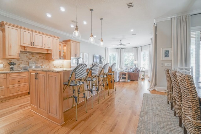 kitchen featuring light stone counters, light hardwood / wood-style flooring, ceiling fan, and decorative light fixtures