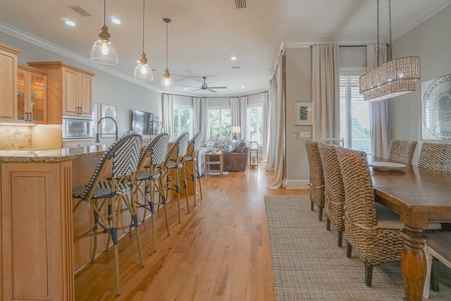 kitchen featuring backsplash, ceiling fan, light brown cabinets, pendant lighting, and light hardwood / wood-style floors