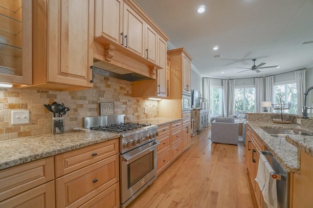 kitchen with light brown cabinets, sink, light stone countertops, light wood-type flooring, and stainless steel appliances