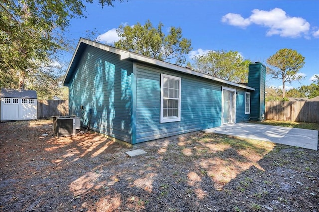 rear view of house with a patio, central AC, and a storage unit