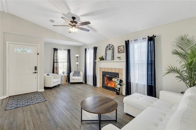 living room with a tile fireplace, hardwood / wood-style floors, ceiling fan, and lofted ceiling