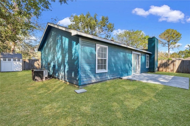 rear view of house with a shed, cooling unit, a patio area, and a lawn