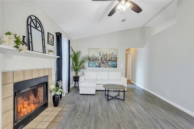 living room featuring a fireplace, ceiling fan, light hardwood / wood-style flooring, and lofted ceiling