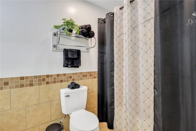 bathroom featuring toilet and tile walls