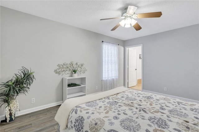 bedroom with hardwood / wood-style floors, ceiling fan, and a textured ceiling