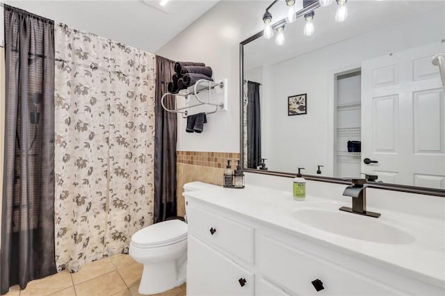 bathroom with walk in shower, tile patterned floors, toilet, vanity, and tile walls